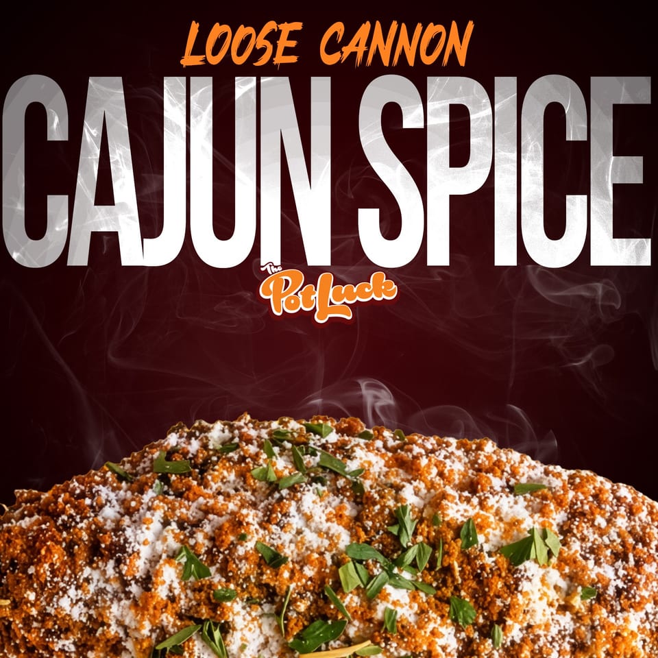 Close-up of a dish heavily seasoned with orange Cajun spice, white powder, and green herbs.