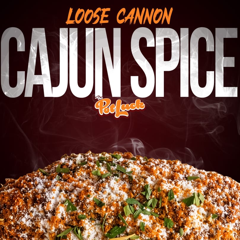 Close-up of a dish heavily seasoned with orange Cajun spice, white powder, and green herbs.